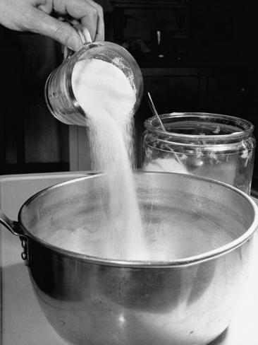 adding sugar to a pot of water on a stove to make sugar adding sugar to a pot of water on a stove to make sugar