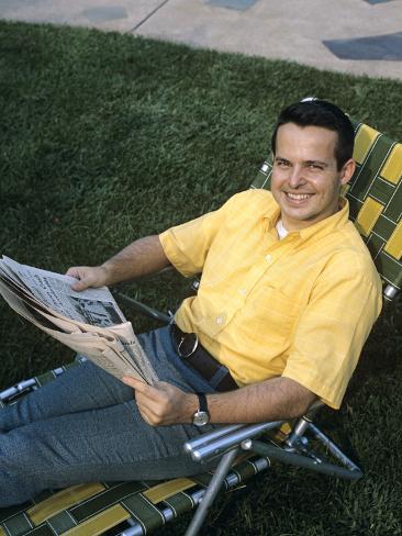 1970s-smiling-man-sitting-in-lawn-chair-relaxing-holding-newspaper.jpg