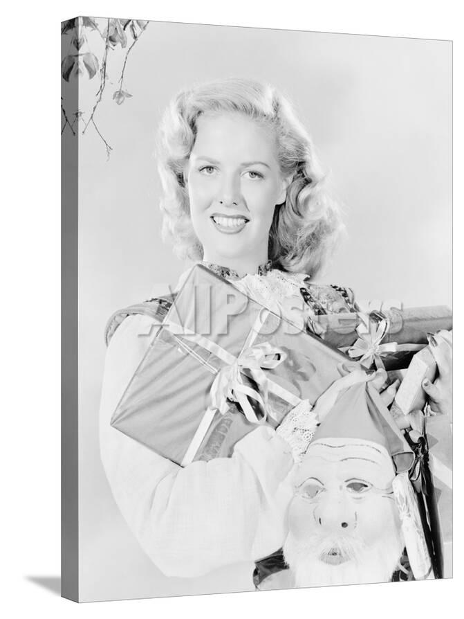 Young Woman Holding An Arm Full Of Presents And A Santa Claus Mask