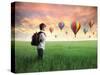 Child Carrying A Backpack Standing On A Green Meadow With Hot-Air Balloons In The Background-olly2-Stretched Canvas