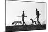 1920s 1930s ANONYMOUS SILHOUETTE MAN AND WOMAN HUNTERS CARRYING GUNS EACH WITH A HUNTING DOG-H. Armstrong Roberts-Mounted Photographic Print