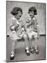 1920s TWO LITTLE GIRLS SITTING ON BENCH EATING ICE CREAM CONES AND TALKING-Panoramic Images-Mounted Photographic Print