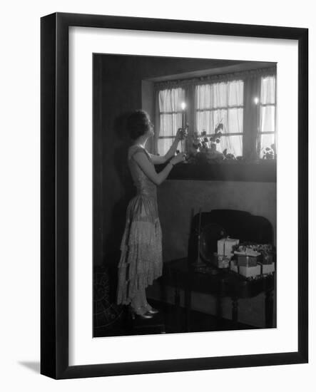 1920s WOMAN PARTY DRESS RUFFLES ON SKIRT PLACING A LIGHTED CANDLE IN WINDOW GIFTS PRESENTS WRAPP...-Panoramic Images-Framed Photographic Print