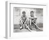 1930s TWO SMILING BOYS STREET HOCKEY PLAYERS SITTING ON CURB WEARING METAL ROLLER SKATES HOLDING...-Panoramic Images-Framed Photographic Print