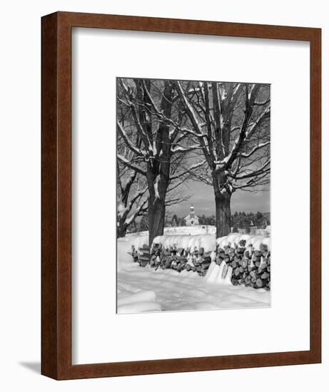 1940s PILE OF SNOW-COVERED FIREWOOD LOGS STACKED BETWEEN TWO TREES WITH COUNTRY CHURCH IN BACKGR...-Panoramic Images-Framed Photographic Print