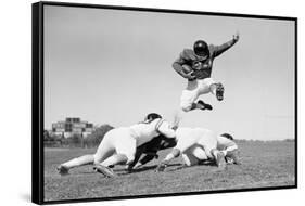 1960s FOOTBALL PLAYER JUMPING OVER BLOCKED PLAYERS-H. Armstrong Roberts-Framed Stretched Canvas