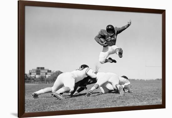 1960s FOOTBALL PLAYER JUMPING OVER BLOCKED PLAYERS-H. Armstrong Roberts-Framed Photographic Print