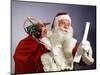 1960s SANTA CLAUS READING THE LIST OF NAUGHTY & NICE SMILING CARRY BAG OF TOYS-Panoramic Images-Mounted Photographic Print