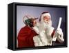 1960s SANTA CLAUS READING THE LIST OF NAUGHTY & NICE SMILING CARRY BAG OF TOYS-Panoramic Images-Framed Stretched Canvas