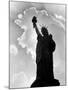 1960s Silhouette of Statue of Liberty with Sun Ray Clouds Behind-null-Mounted Photographic Print