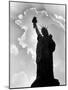 1960s Silhouette of Statue of Liberty with Sun Ray Clouds Behind-null-Mounted Photographic Print