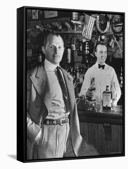 21 Club's Jack Kriendler Relaxing at Bar with Drink, Bartender Holding Bottle on Other Side of Bar-Eric Schaal-Framed Stretched Canvas