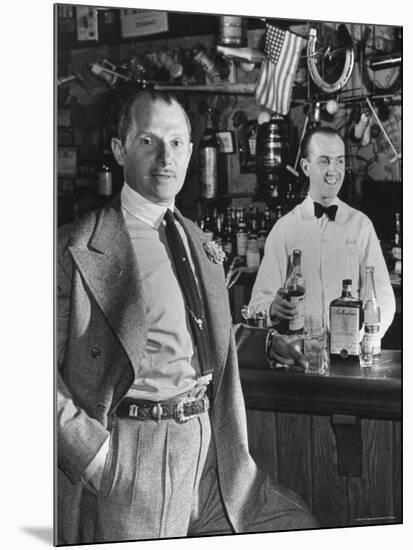 21 Club's Jack Kriendler Relaxing at Bar with Drink, Bartender Holding Bottle on Other Side of Bar-Eric Schaal-Mounted Premium Photographic Print