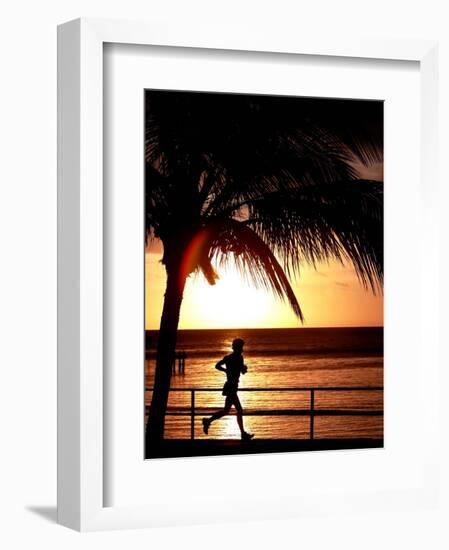 A Afternoon Runner Passes Under a Palm Tree as the Sun Sets Behind-null-Framed Photographic Print