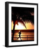 A Afternoon Runner Passes Under a Palm Tree as the Sun Sets Behind-null-Framed Photographic Print