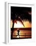 A Afternoon Runner Passes Under a Palm Tree as the Sun Sets Behind-null-Framed Photographic Print