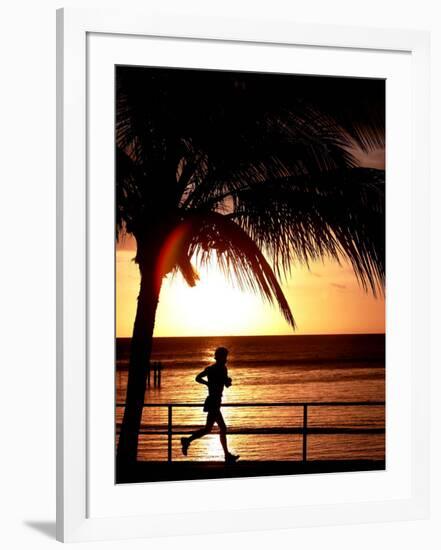 A Afternoon Runner Passes Under a Palm Tree as the Sun Sets Behind-null-Framed Photographic Print