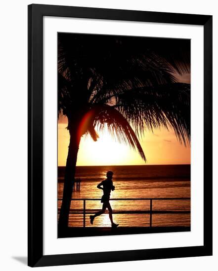 A Afternoon Runner Passes Under a Palm Tree as the Sun Sets Behind-null-Framed Photographic Print