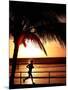 A Afternoon Runner Passes Under a Palm Tree as the Sun Sets Behind-null-Mounted Photographic Print