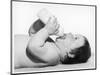 A Baby Lies on His Back Drinking Milk from His Bottle-null-Mounted Photographic Print