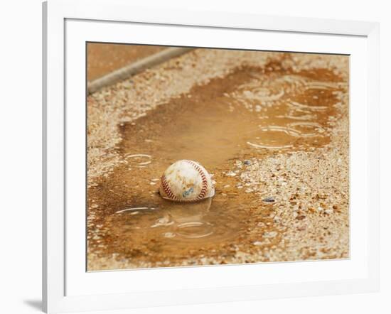 A Baseball Sits in a Puddle-null-Framed Photographic Print