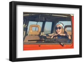 A Beautiful Teenage Girl in Sunglasses and a Blue T-Shirt Sits behind the Wheel and Enjoys the Jour-Akimicheva Olga-Framed Photographic Print