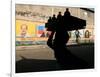 A Boy Carrying Bottles on His Head Passes by a Wall with Pictures of Haitian President Renel Preval-Ariana Cubillos-Framed Photographic Print