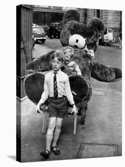 A Boy Gives a Ride to a Little Girl and a 9-Foot Teddy Bear at the Opening of the British Toy Fair-null-Stretched Canvas