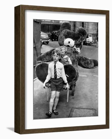 A Boy Gives a Ride to a Little Girl and a 9-Foot Teddy Bear at the Opening of the British Toy Fair-null-Framed Photographic Print