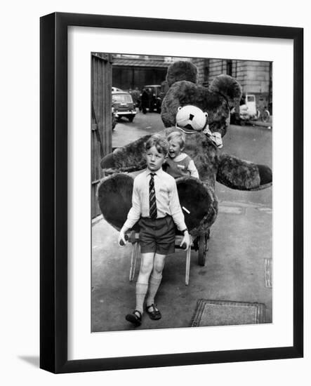 A Boy Gives a Ride to a Little Girl and a 9-Foot Teddy Bear at the Opening of the British Toy Fair-null-Framed Photographic Print
