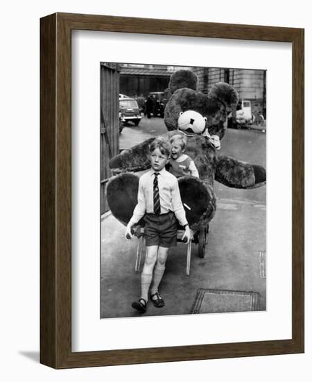 A Boy Gives a Ride to a Little Girl and a 9-Foot Teddy Bear at the Opening of the British Toy Fair-null-Framed Photographic Print