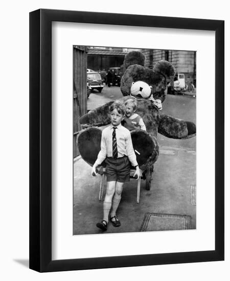 A Boy Gives a Ride to a Little Girl and a 9-Foot Teddy Bear at the Opening of the British Toy Fair-null-Framed Photographic Print