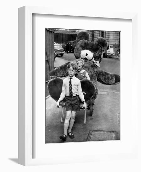 A Boy Gives a Ride to a Little Girl and a 9-Foot Teddy Bear at the Opening of the British Toy Fair-null-Framed Photographic Print