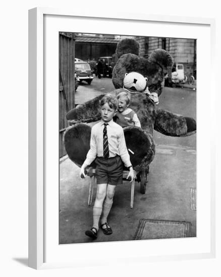 A Boy Gives a Ride to a Little Girl and a 9-Foot Teddy Bear at the Opening of the British Toy Fair-null-Framed Photographic Print