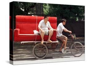 A Chinese Man Rides on a Sofa as Another Pedals a Delivery Tricycle-null-Stretched Canvas