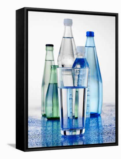 A Glass in Front of Mineral Water Bottles-Alexander Feig-Framed Stretched Canvas