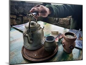 A Hand on a Teapot and Yerba Mate at Refugio Piltriquitron in the Andes of Patagonia, Argentina-Maureen Eversgerd-Mounted Photographic Print