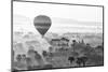 A hot air balloon flies over a trees and a temple at sunrise on a misty morning, Bagan, Myanmar-Tim Mannakee-Mounted Photographic Print