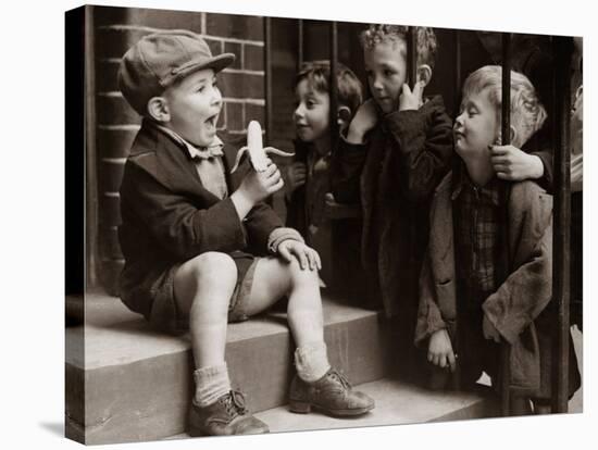 A Little Boy Holding a Banana Whilst Other Children Gaze Longingly at It-null-Stretched Canvas