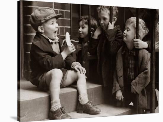 A Little Boy Holding a Banana Whilst Other Children Gaze Longingly at It-null-Stretched Canvas