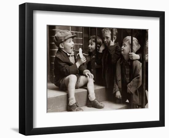 A Little Boy Holding a Banana Whilst Other Children Gaze Longingly at It-null-Framed Photographic Print