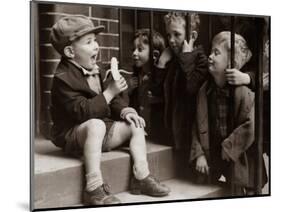 A Little Boy Holding a Banana Whilst Other Children Gaze Longingly at It-null-Mounted Photographic Print
