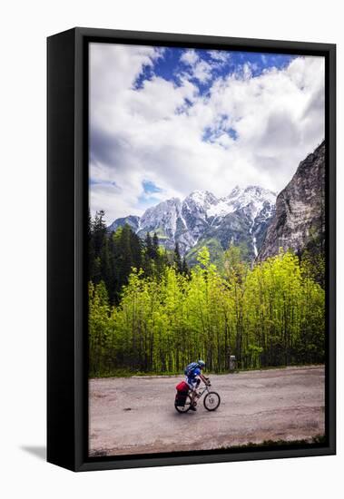 A Lone Cyclist Travels Along a Mountain Road with Trees and the Julian Alps in the Background-Sean Cooper-Framed Stretched Canvas