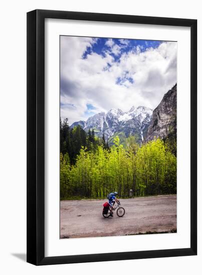 A Lone Cyclist Travels Along a Mountain Road with Trees and the Julian Alps in the Background-Sean Cooper-Framed Photographic Print