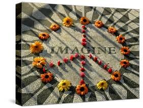 A Makeshift Peace Sign of Flowers Lies on Top John Lennon's Strawberry Fields Memorial-null-Stretched Canvas