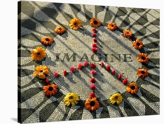 A Makeshift Peace Sign of Flowers Lies on Top John Lennon's Strawberry Fields Memorial-null-Stretched Canvas