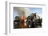 A Man Makes His Way Out of Flood Waters as Fire Burns Down a Home-Shannon Stapleton-Framed Photographic Print