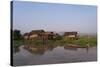 A man paddles his canoe past one of the floating villages on Inle Lake, Myanmar (Burma), Asia-Alex Treadway-Stretched Canvas