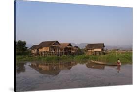 A man paddles his canoe past one of the floating villages on Inle Lake, Myanmar (Burma), Asia-Alex Treadway-Stretched Canvas