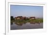 A man paddles his canoe past one of the floating villages on Inle Lake, Myanmar (Burma), Asia-Alex Treadway-Framed Photographic Print